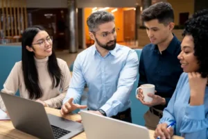 A diverse team of professionals collaborating on a project with laptops and documents in a modern office, focusing on teamwork and effective communication.