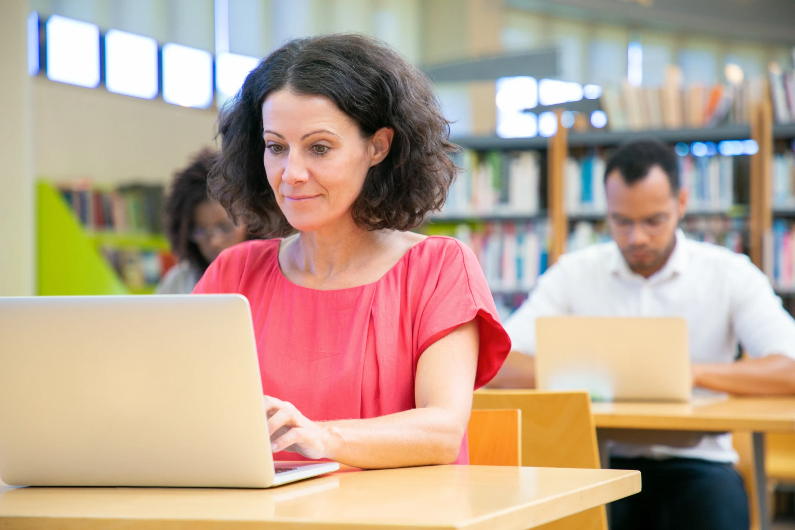 Focused woman using a laptop in a library, representing digital learning. Keywords: videographer, videography, digital marketing, Mumbai.