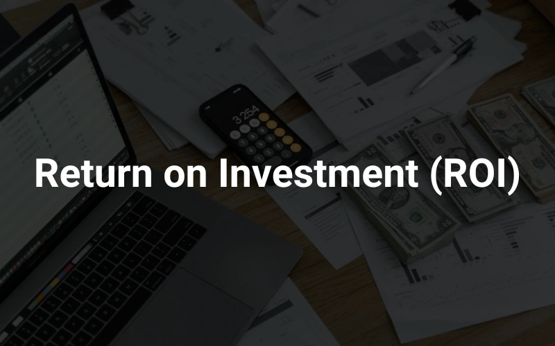 a laptop computer placed on top of a wooden desk with papers money spread around in the background, highlighting the text "ROI (Return on Investment)."